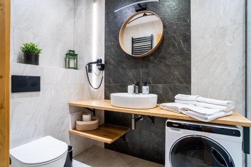 a bathroom with a sink and a washing machine at Euphoria Mountains by Apart Concept Podhale in Kościelisko