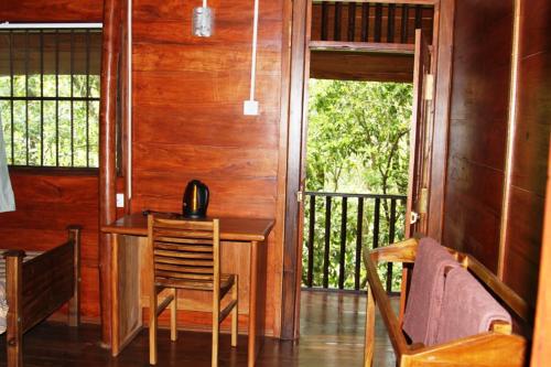 a room with a table and chairs on a porch at Birds Paradise Hotel in Kudawe