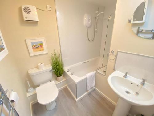 a bathroom with a sink and a toilet and a bath tub at Norfolk Chapel Cottages in Docking