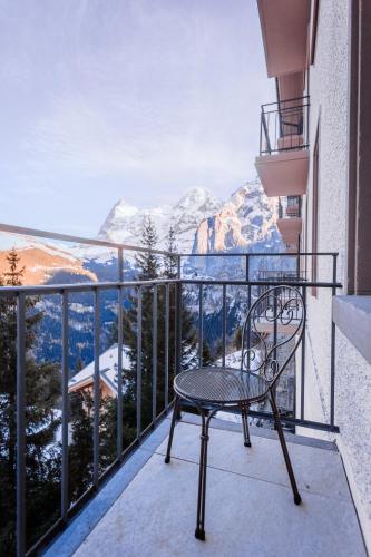 a chair on a balcony with a view of mountains at Hotel Mürren Palace in Mürren