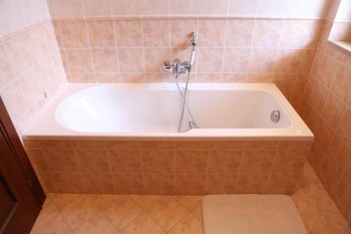 a bath tub with a shower in a tiled bathroom at Centauro by PizzoApartments in Pizzo