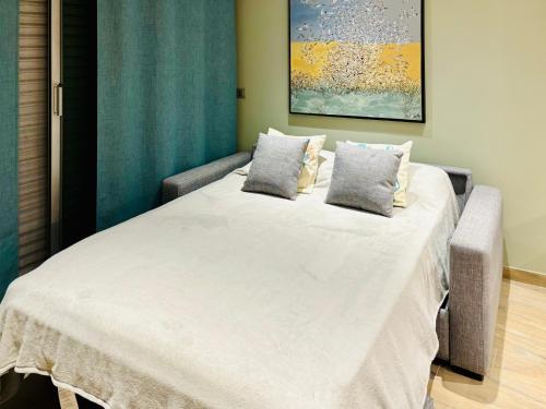 un grand lit blanc avec deux oreillers dessus dans l'établissement Bellissime studio tout confort vue sur la marina et la piscine, à Mandelieu-la-Napoule