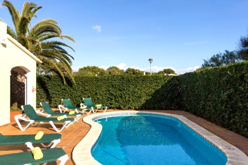 una piscina con tumbonas y sillas alrededor en Villa Menorca Cleo by Mauter Villas, en Cala Blanca
