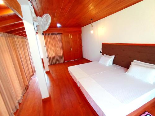 a bedroom with two beds and a wooden floor at Thusara Guesthouse in Mirissa