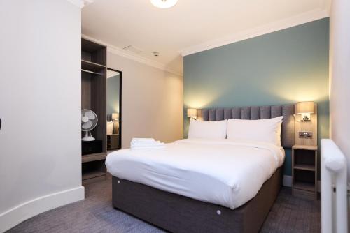 a bedroom with a large bed with white sheets at Prince William Hotel in London