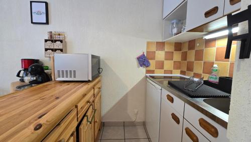 a kitchen with a microwave on a wooden counter at Cosy'PY in Bagnères-de-Bigorre