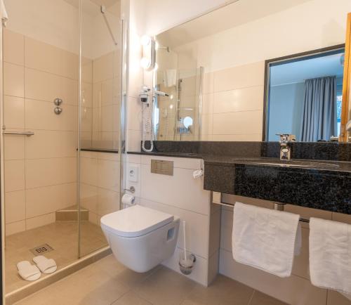 a bathroom with a toilet and a sink and a mirror at Akzent Hotel Gut Höing in Unna