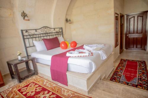 Un dormitorio con una gran cama blanca con almohadas rojas. en Güven Cave Hotel, en Göreme