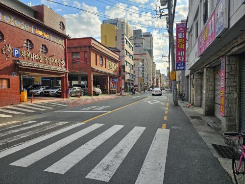 an empty city street with a crosswalk on the road at Busan Subway 6min #2 Rooms #2 Queen Beds #Hotel Bedding #OTT #Table#1st Floor in Busan