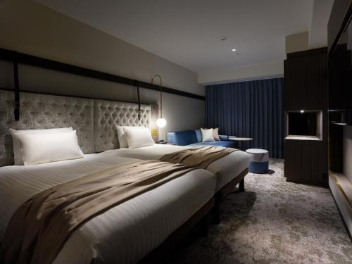 a hotel room with two beds and a television at Mitsui Garden Hotel Sapporo West in Sapporo