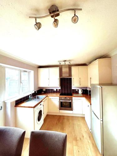 a kitchen with white cabinets and a washer and dryer at 2 Bedroom House off A12 Colchester in Lexden