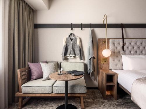 a bedroom with a bed and a couch and a table at Mitsui Garden Hotel Sapporo West in Sapporo