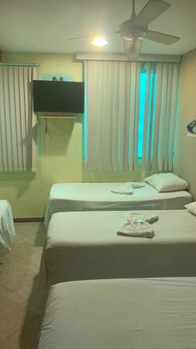 a room with three beds and a ceiling fan at Suítes felicidade Rio Centro in Rio de Janeiro