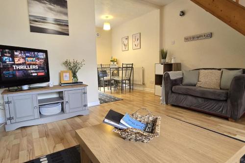 a living room with a tv and a couch and a table at Lovely Holiday Home to explore beautiful West Wales in Carmarthen