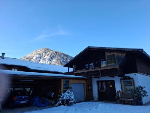 a house in the snow with a mountain in the background at Ferienwohnung zum Urfall -- Sommerbergbahnen inklusive !!! in Tannheim