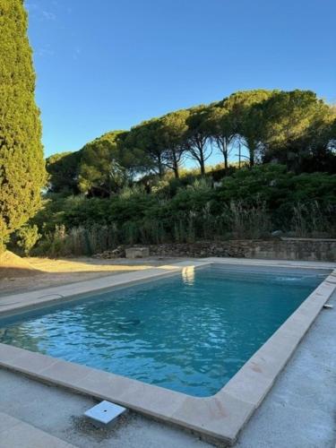 une piscine en face d'une colline plantée d'arbres dans l'établissement Domaine La Grange, à Gabian