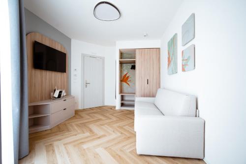 a living room with a white chair and a television at Hotel Cavalieri Palace & Suites in Lido di Jesolo
