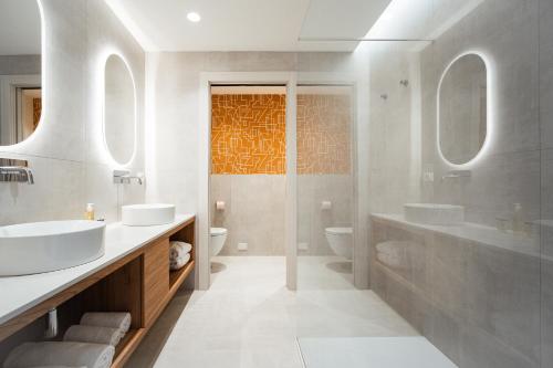 a white bathroom with two sinks and a shower at Hotel Cavalieri Palace & Suites in Lido di Jesolo