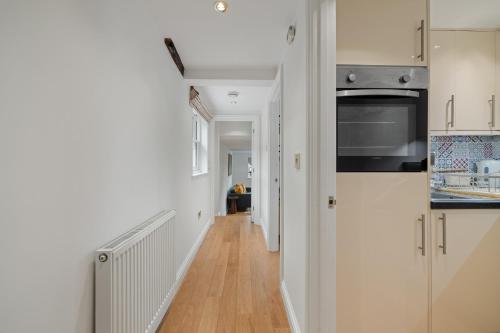 a kitchen with white walls and a wooden floor at City Centre Apartment with Cathedral Views and FREE Parking- Self check in in Chichester