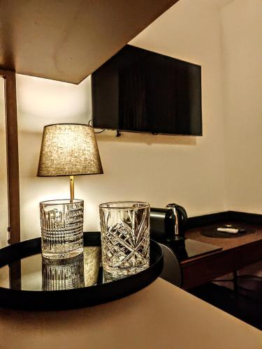 a table with two glasses and a lamp on it at Alloggi Tosca Airport Lodges in Ronchi dei Legionari