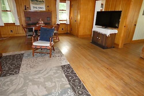 a living room with a television and a table with chairs at Lakeside Cottage on Torch Lake in Alden