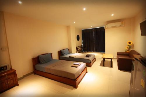 a hotel room with two beds and a television at Sorot Darika Jomtien Beach in Jomtien Beach