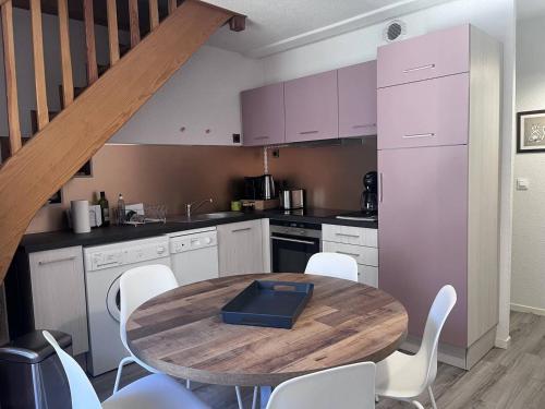 - une cuisine avec une table en bois et des chaises blanches dans l'établissement Duplex charmant à Cauterets, proche commerces et téléphérique - FR-1-812-82, à Cauterets