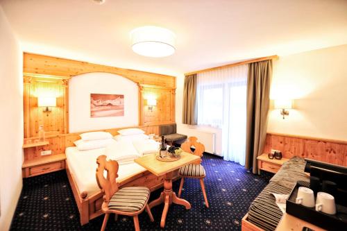 a hotel room with a bed and a table and chairs at Hotel Garni Bellevue in Ischgl