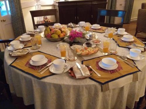 a table with plates and bowls of fruit on it at Chowkidinghee Heritage Tea Bungalow in Dibrugarh