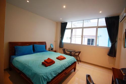 a bedroom with a bed with two orange towels on it at Sorot Darika Jomtien Beach in Jomtien Beach