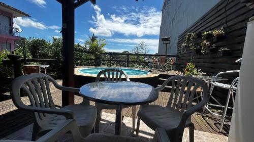 a table and chairs on a patio with a pool at Kitnet 1 na Joaquina com piscina in Florianópolis