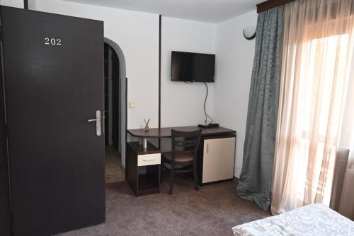 a hotel room with a desk and a television at Къща за Гости БАРБЕЛ in Golyam Izvor