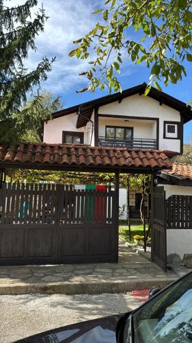 a house with a black gate and a fence at Къща за Гости БАРБЕЛ in Golyam Izvor