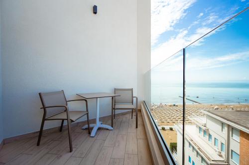 a balcony with a table and chairs and a view of the ocean at Hotel Cavalieri Palace & Suites in Lido di Jesolo