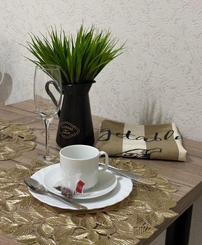 a table with a cup and a plate and a vase at Новая 1 комнатная квартира in Uralsk