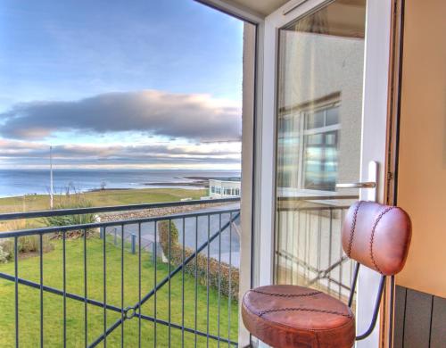 a room with a balcony with a view of the ocean at No10 The Links Apartment, Brora in Brora
