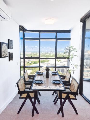 a dining room with a table and chairs and a large window at Horizon Suite on the TOP in Olympic Park in Sydney