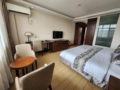a hotel room with a bed and a desk and chair at Dmall Hotel in Kigali