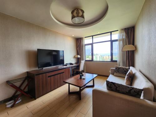a living room with a couch and a flat screen tv at Dmall Hotel in Kigali