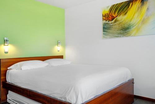 Un dormitorio con una cama blanca con un cuadro en la pared. en The Wave House - Seaside Haven, en Jardim do Mar