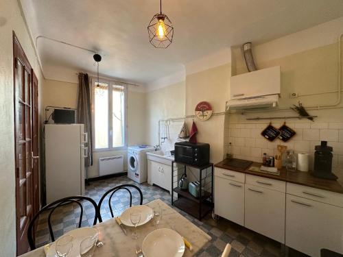 une cuisine avec une table, des chaises et un réfrigérateur dans l'établissement Chez Monique - Appartement T2 au cœur du centre ville historique - proche Mairie et Cardeurs, à Aix-en-Provence