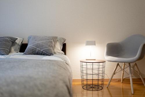 a bedroom with a bed and a chair and a lamp at Belle Lead 105 in Tokyo