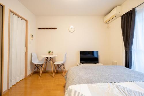 a bedroom with a bed and a table and a tv at Belle Lead 105 in Tokyo