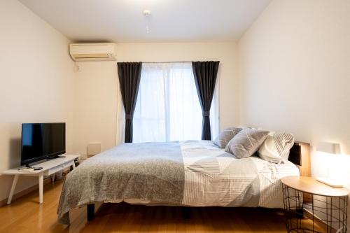 a bedroom with a bed with a television and a window at Belle Lead 105 in Tokyo