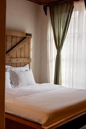 a bed with a wooden headboard and a window at Bujtina Jaki in Gjakove