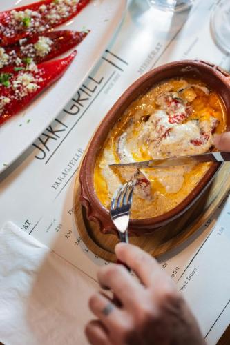a person eating a bowl of food with a fork and knife at Bujtina Jaki in Gjakove