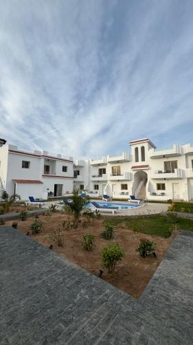 a large white apartment building with a swimming pool at Desert Hotel Dahab in Dahab