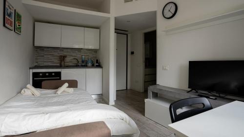 a bedroom with a large bed and a kitchen at Free Parking - San Gerardo cosy apartment in Vedano al Lambro