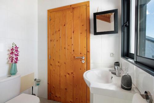 Un baño con puerta de madera y lavabo. en The Wave House - Oceanfront, en Jardim do Mar