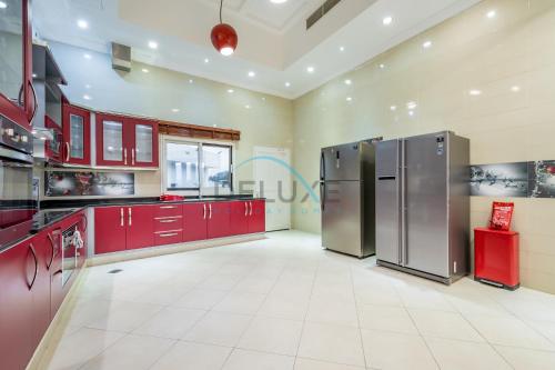 a kitchen with red cabinets and stainless steel appliances at Country-side Farm Villa Best for Group Gatherings by Deluxe Holiday Homes in Fujairah
